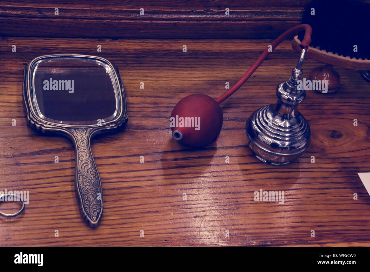 High Angle View Of Perfume Sprayer By Hand Mirror On Wooden Table At Barbershop Stock Photo