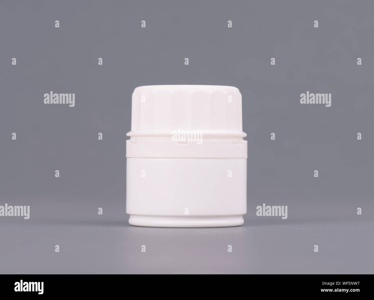 Blank medium size medicine white plastic packaging bottles for cosmetics, vitamins, pills or capsules. Packaging on gray background Stock Photo