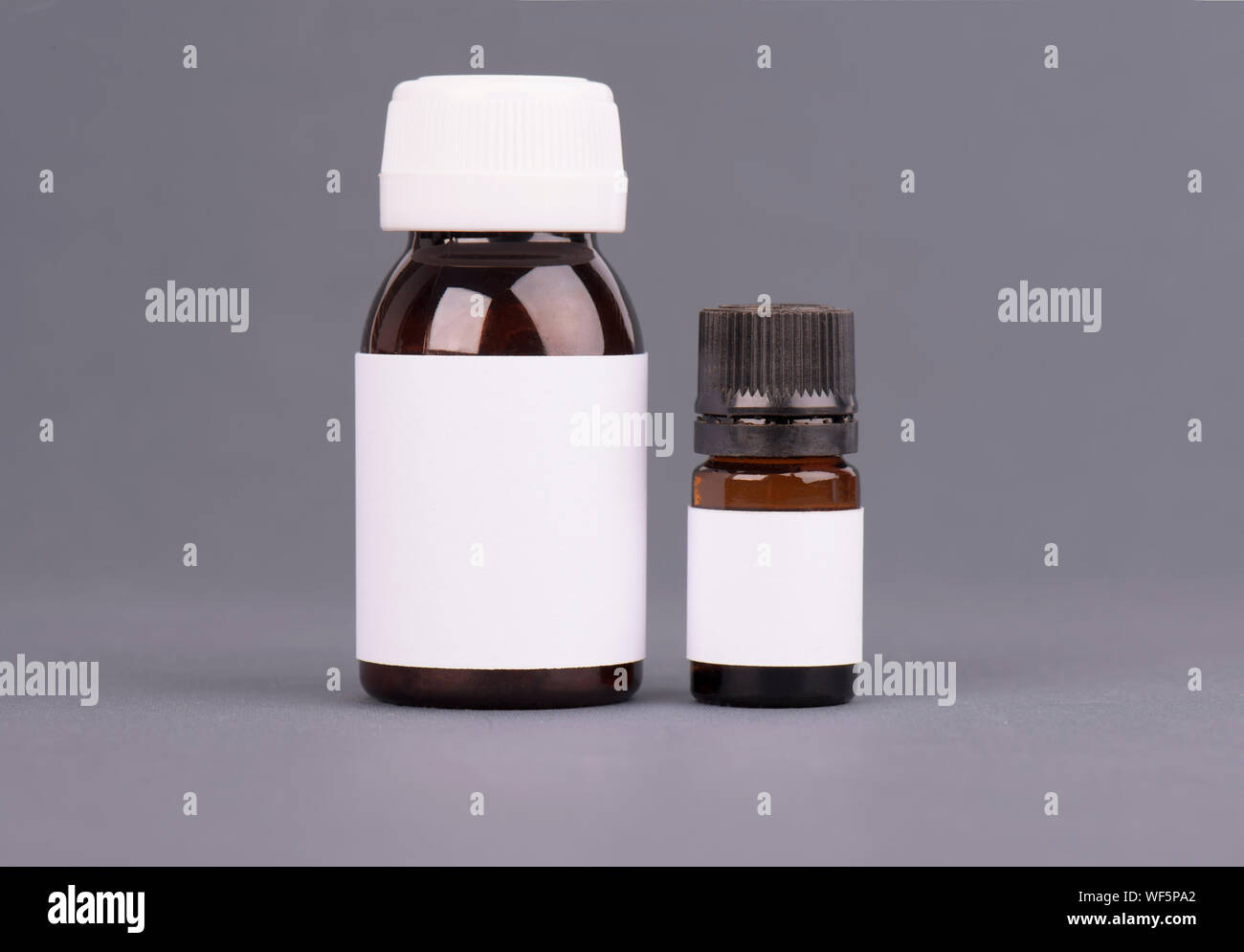 Blank big and medium size medicine white plastic packaging bottles for cosmetics, vitamins, pills or capsules. Packaging on gray background Stock Photo
