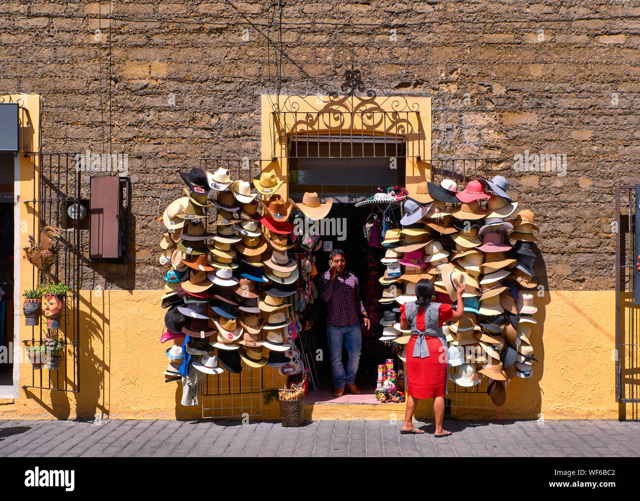 San Pedro Cholula, Mexico, September 30, 2019 - Shop of traditional Mexican hats in Avenida Morelos street of Cholula with a woman who orders her hair and a salesman at door. Stock Photo