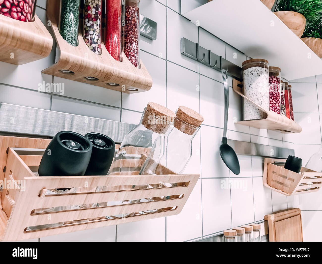 Modern scandinavian style kitchen wall with wooden shelves, tools and  bottles with spices. White tile background. Mobile photo Stock Photo - Alamy, image size:1300x1065