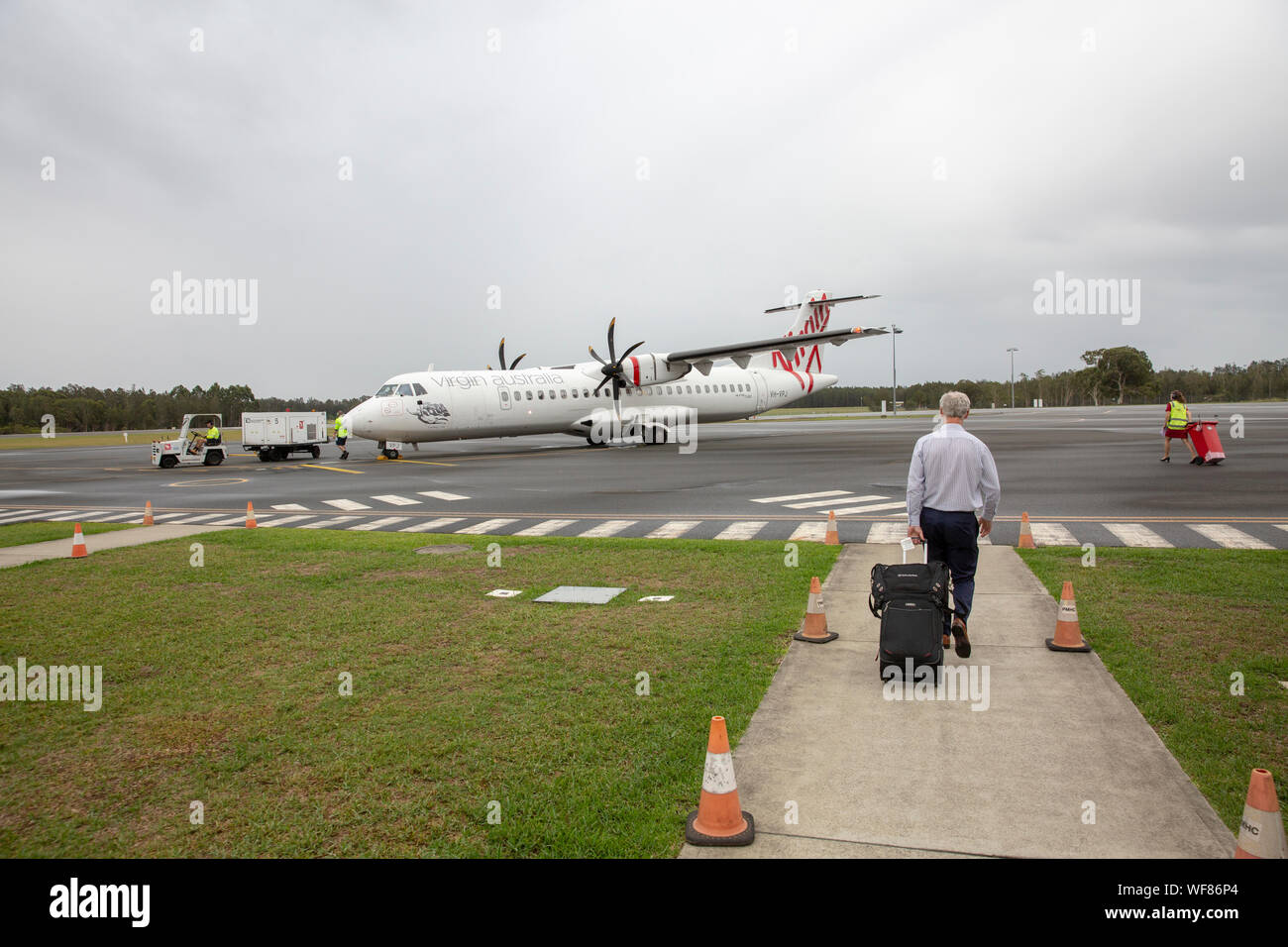 Australian business man airside at the airport carrying luggage to board Virgin australia plane Stock Photo