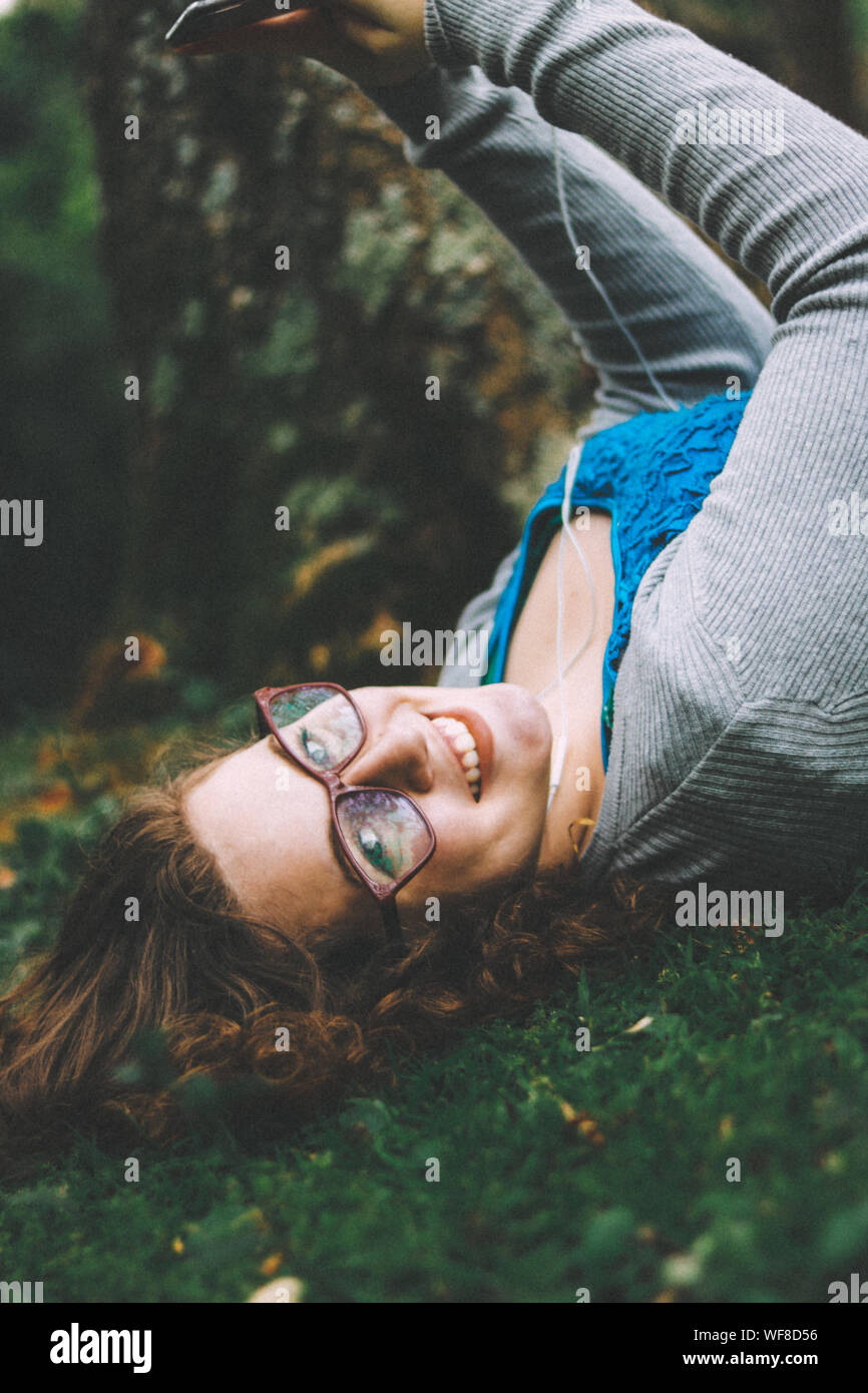 Portrait Of Teenage Girl Eyeglasses While Lying On Grass Stock Photo