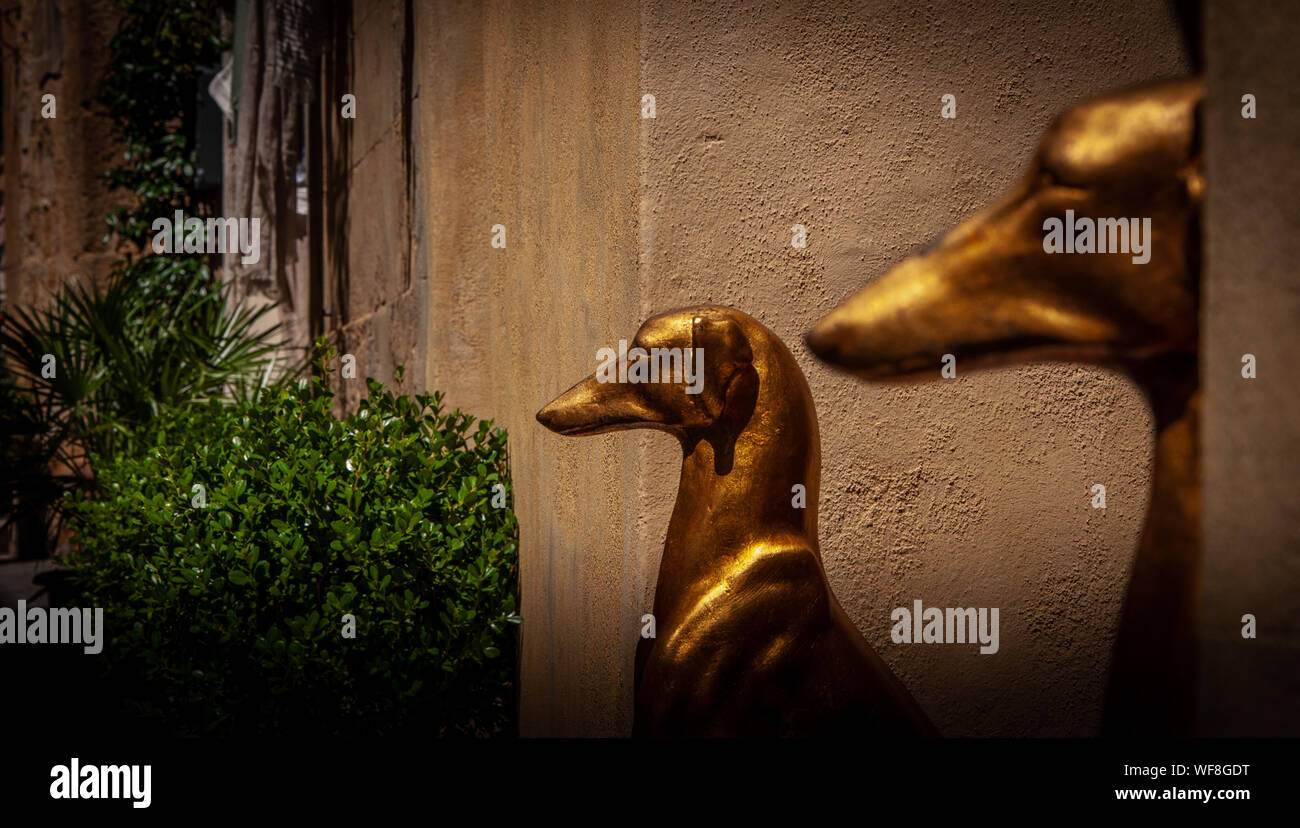 Golden statues of dogs stand to attention outside a doorway Stock Photo