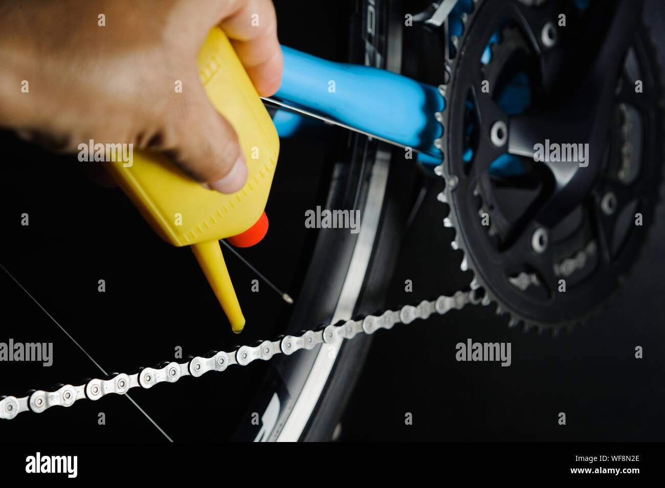 Mechanic oiling bicycle chain and gear with oil. Studio shot Stock Photo