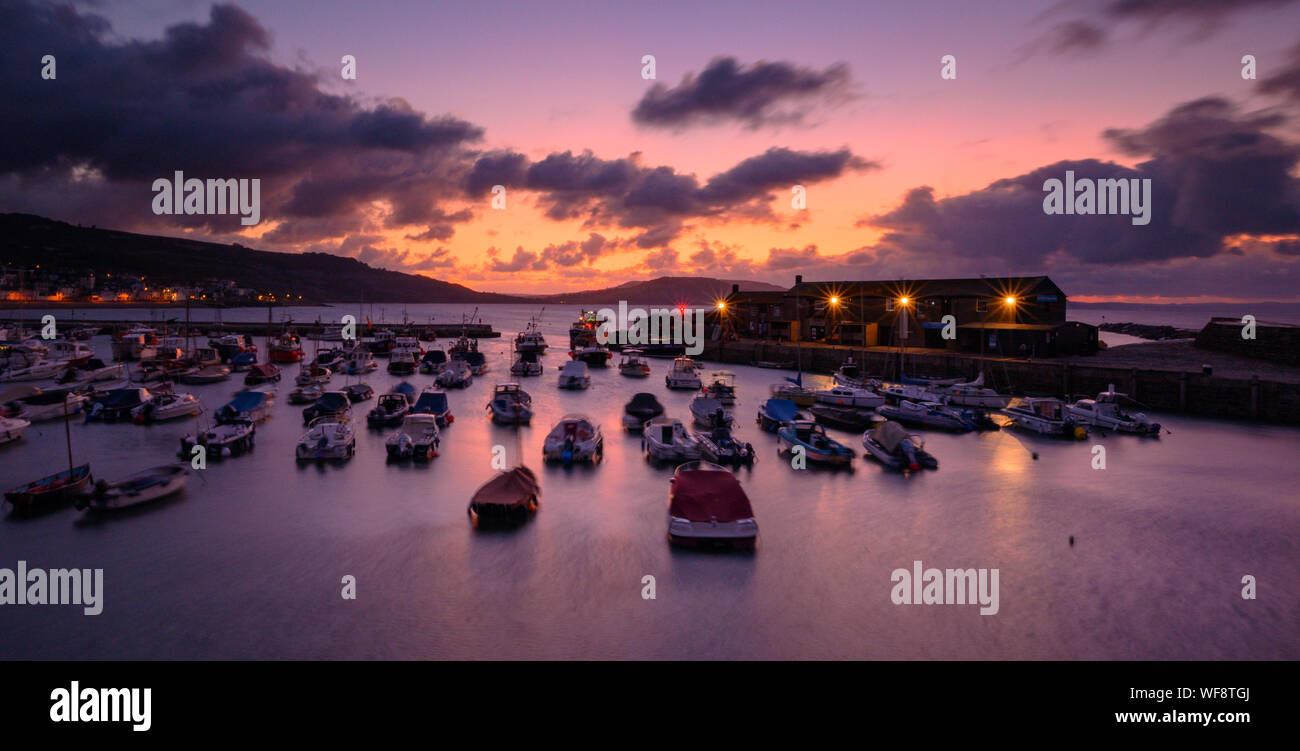 Lyme Regis, Dorset, UK.  31st August 2019. UK Weather: Spectacular sunrise over the historic Cobb Harbour at the coastal resort town of Lyme Regis.  There was a hint of autumn in the air as the sky glowed with dramatic pre sunrise colour on the last day of summer. Credit: Celia McMahon/Alamy Live News. Stock Photo