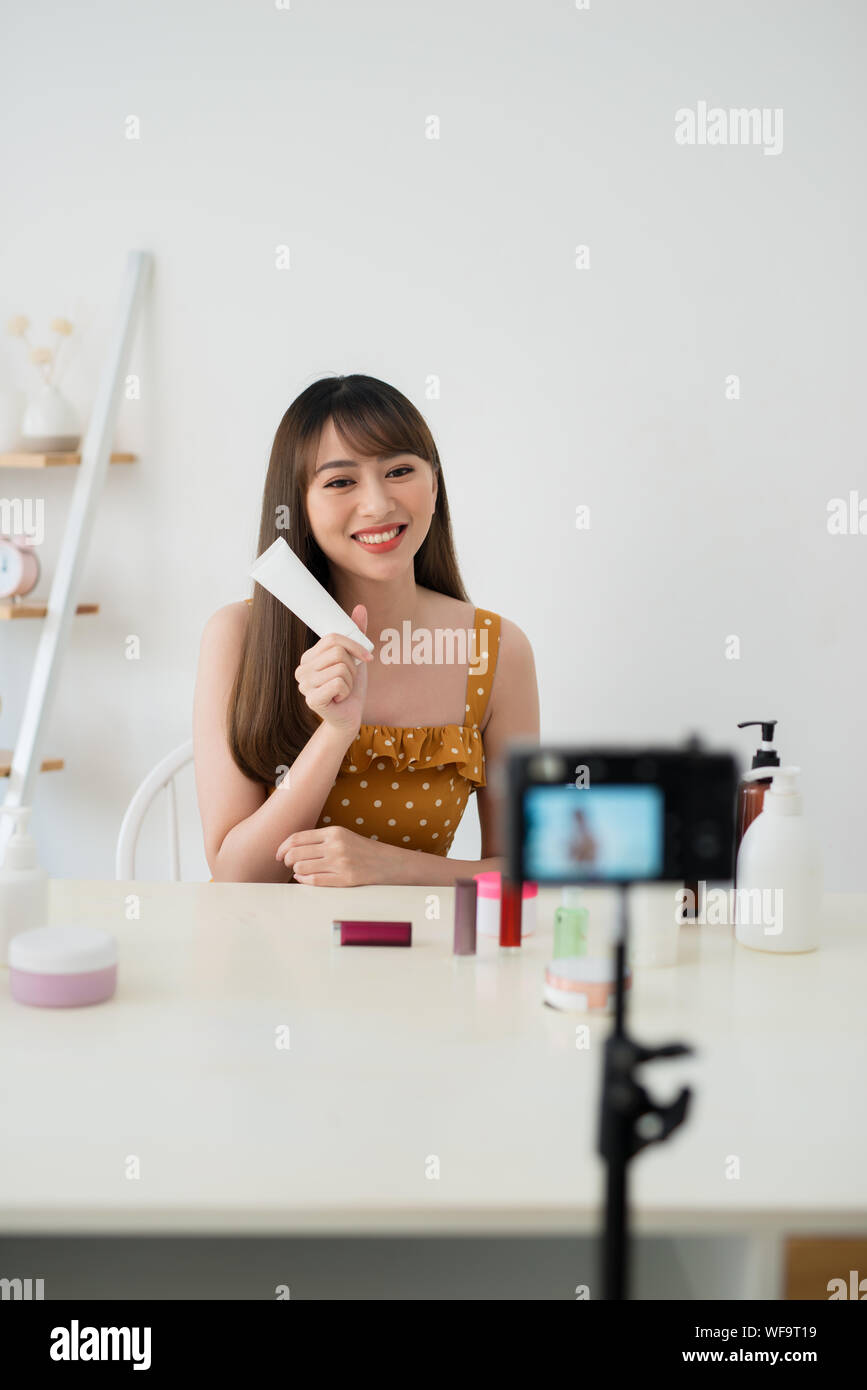 Young female blogger with makeup cosmetics recording video at home Stock Photo
