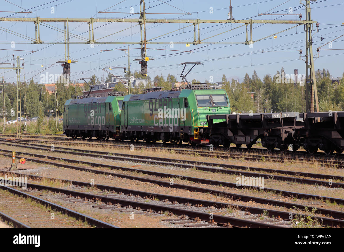 Lulea, Sweden - August 20, 2019: Two Green Cargo electric locomitives class Re pulling flat wagons loaded with steel from the nearby SSAB steel mill. Stock Photo