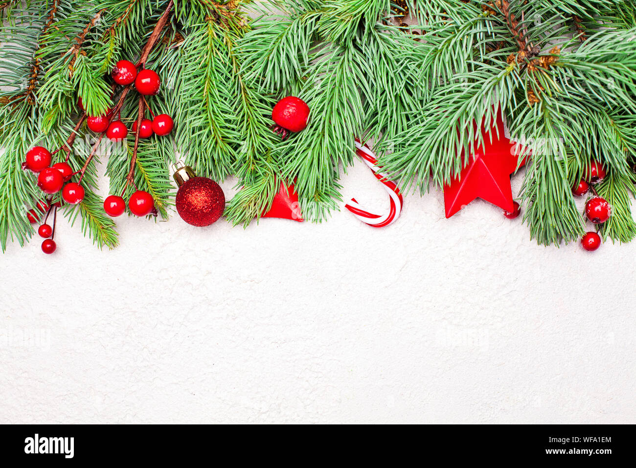 Xmas border with green Xmas fir branch, red holly berries and baubles ...