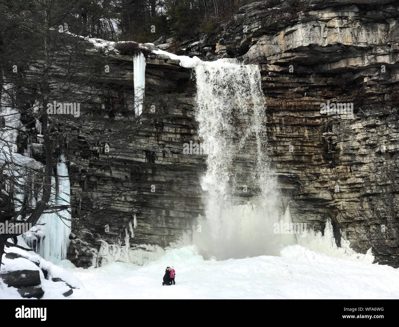 Woman With Child Against Waterfall During Winter Stock Photo