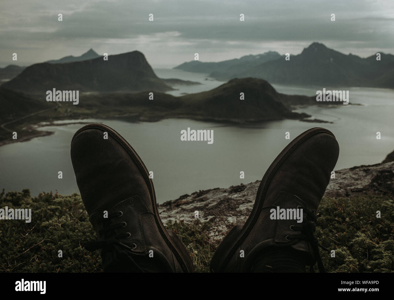 Low Section Of Shoes By Lake Against Mountain Range Stock Photo