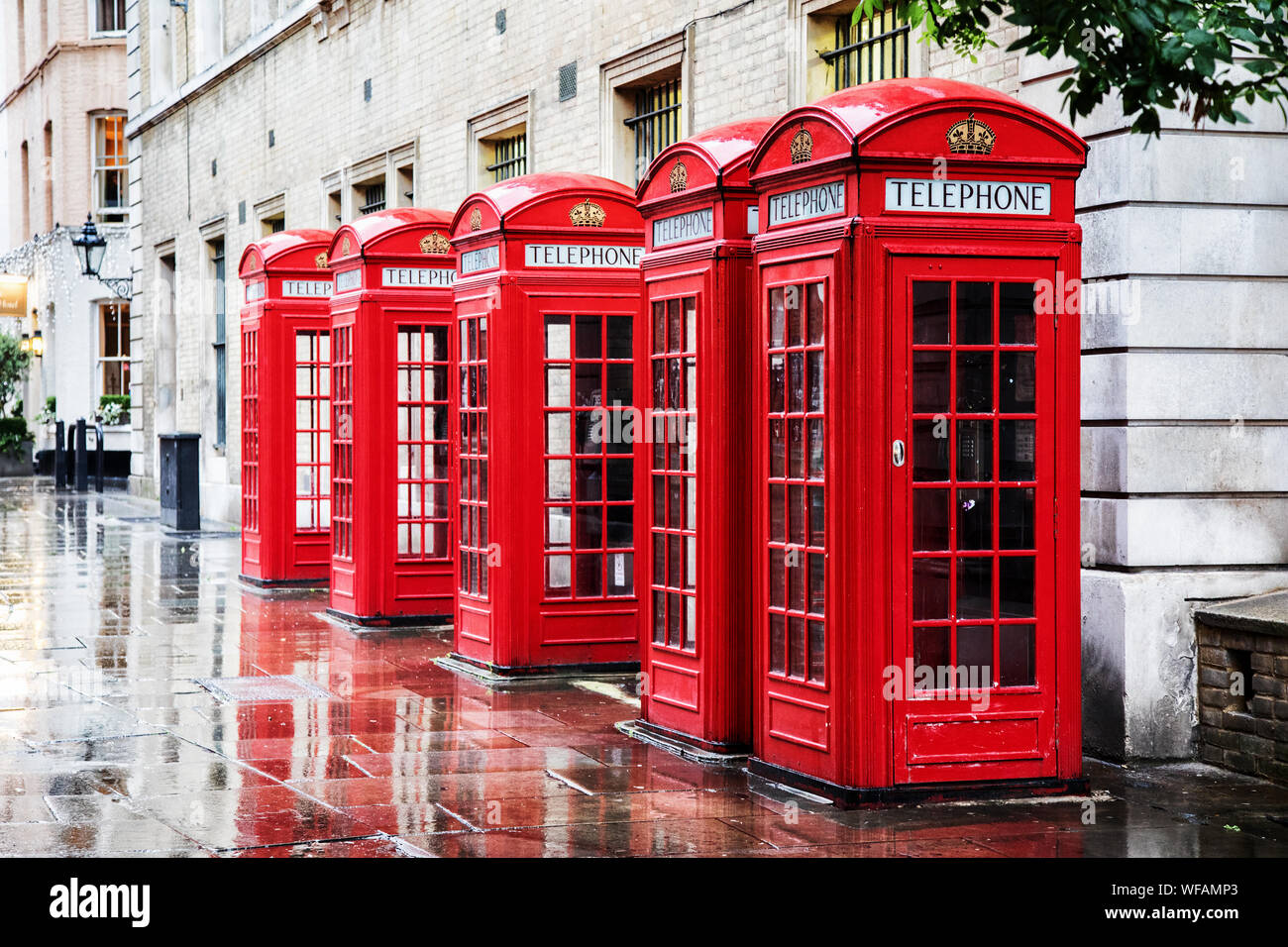 Five British red phone boxes in a row. A line of phone booths in Covent garden after the rain. Stock Photo
