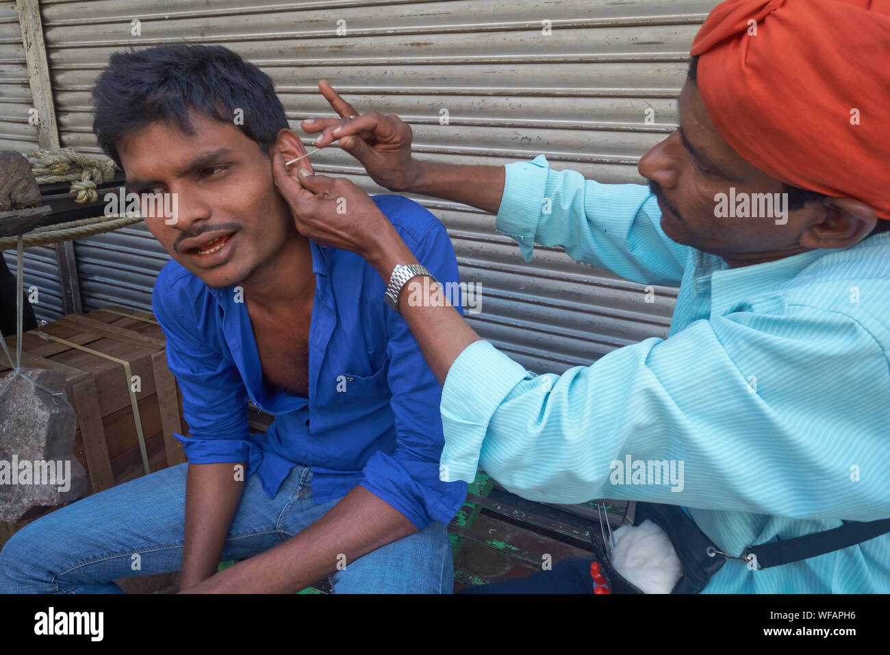 An ear cleaner wearing the profession's customary red turban cleaning a
