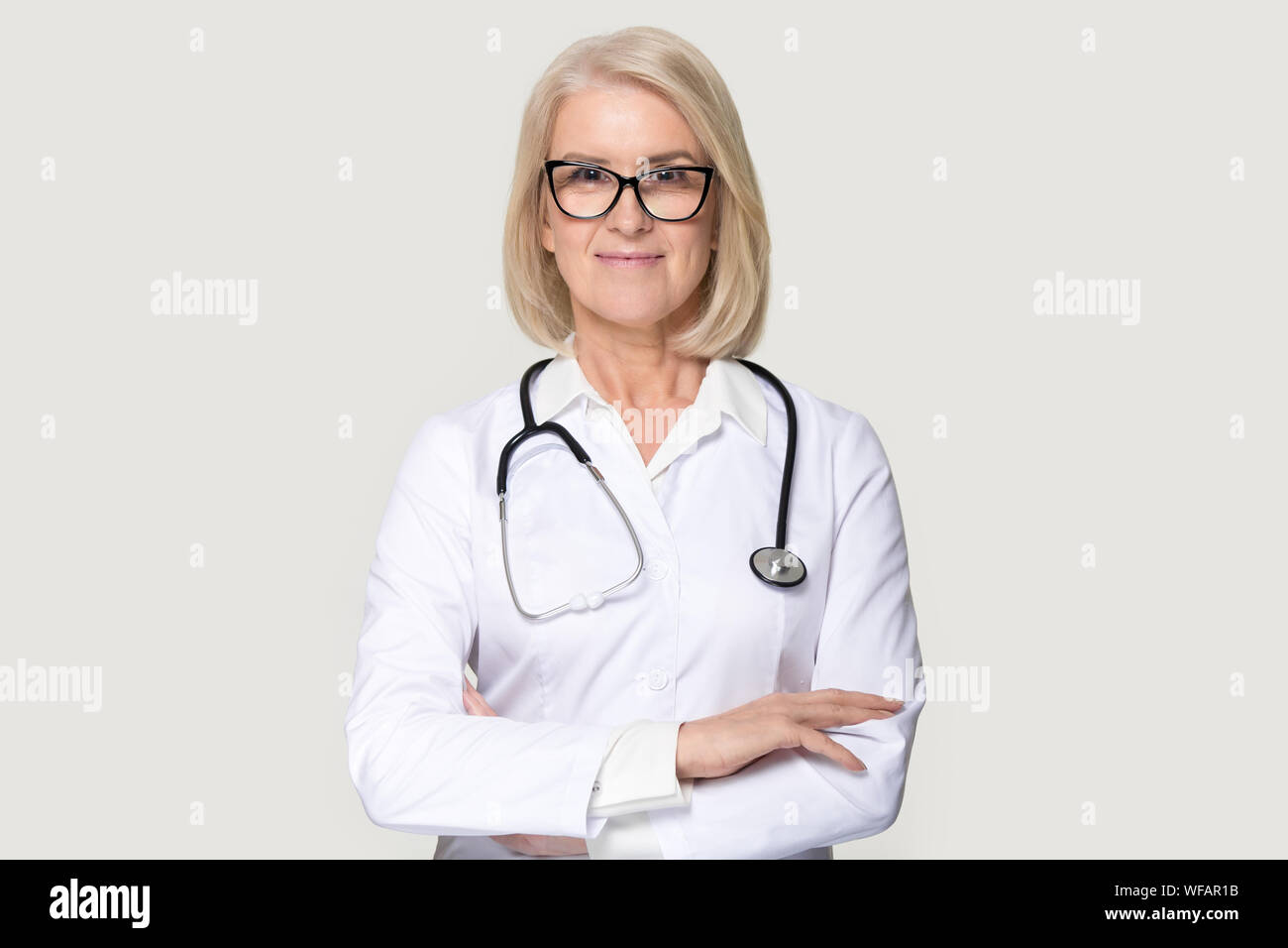 Portrait of mature female doctor isolated on grey background Stock ...