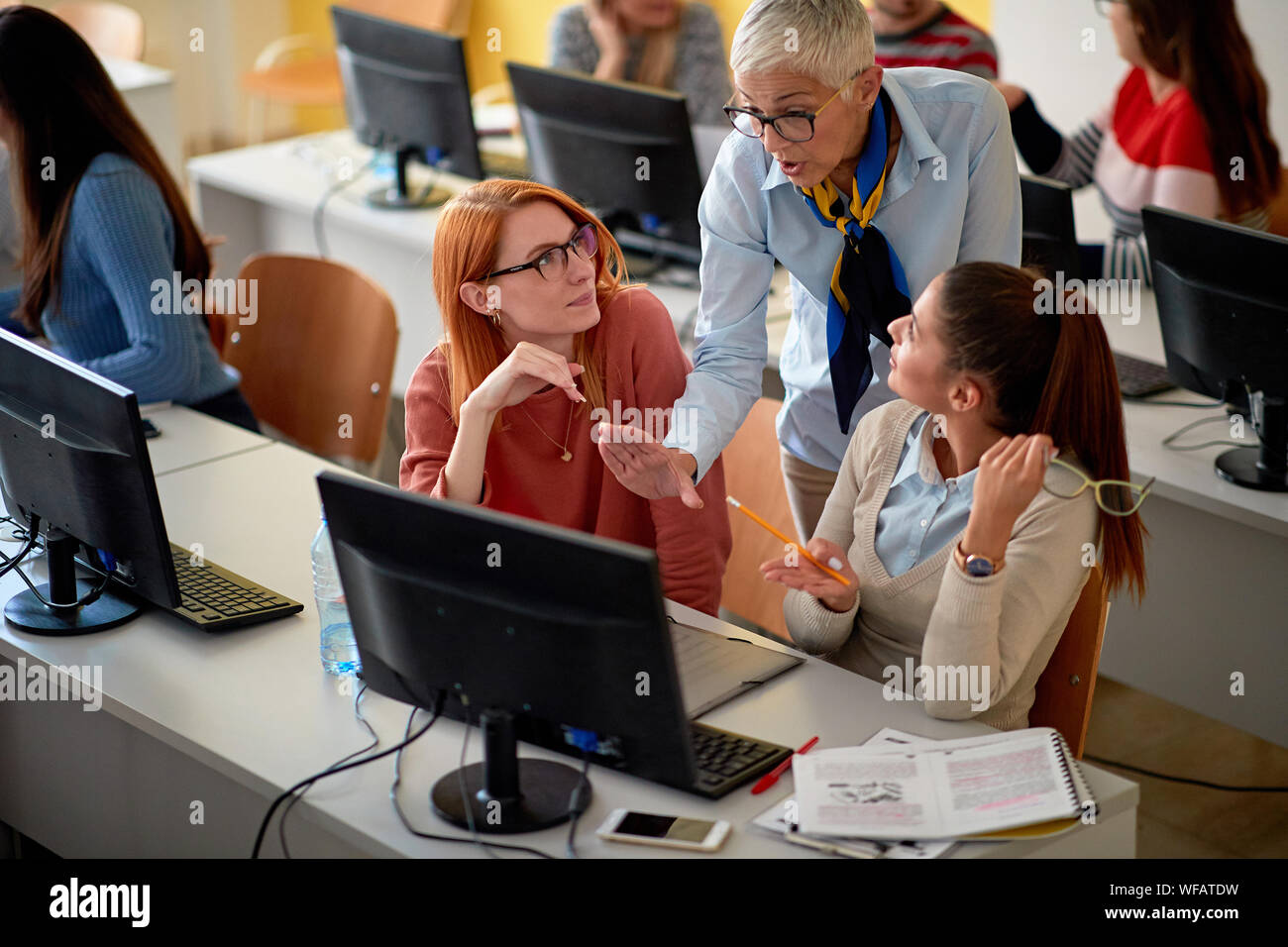 teacher helping smiling students on project Stock Photo