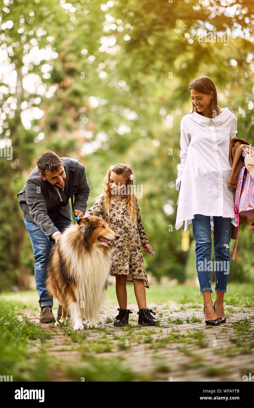 Happy mother and father with their daughter is having fun with dog in ...