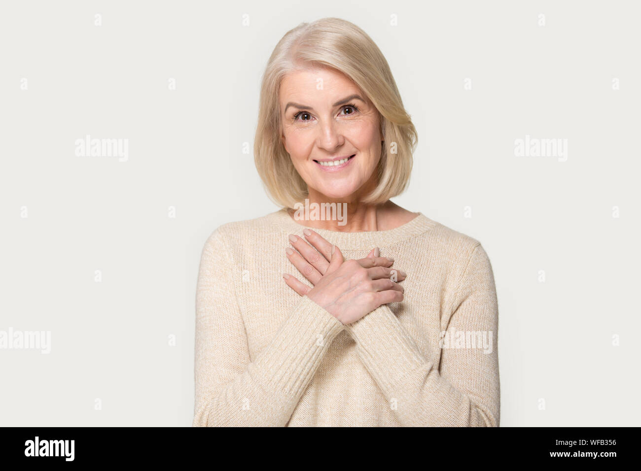 Grateful senior woman with hands on chest feel thankful Stock Photo