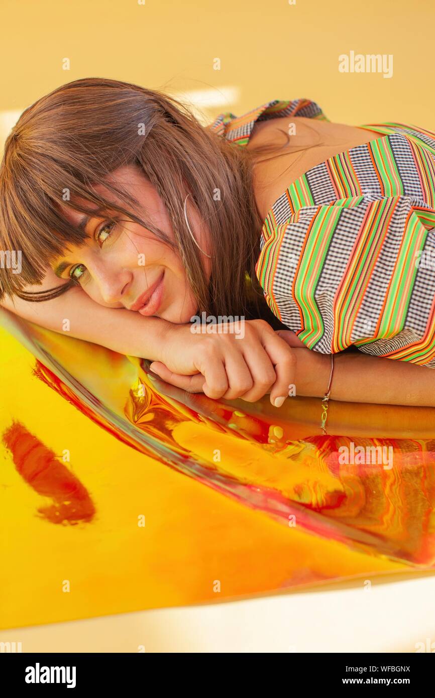 Portrait of a smiling woman lying on holographic foil Stock Photo