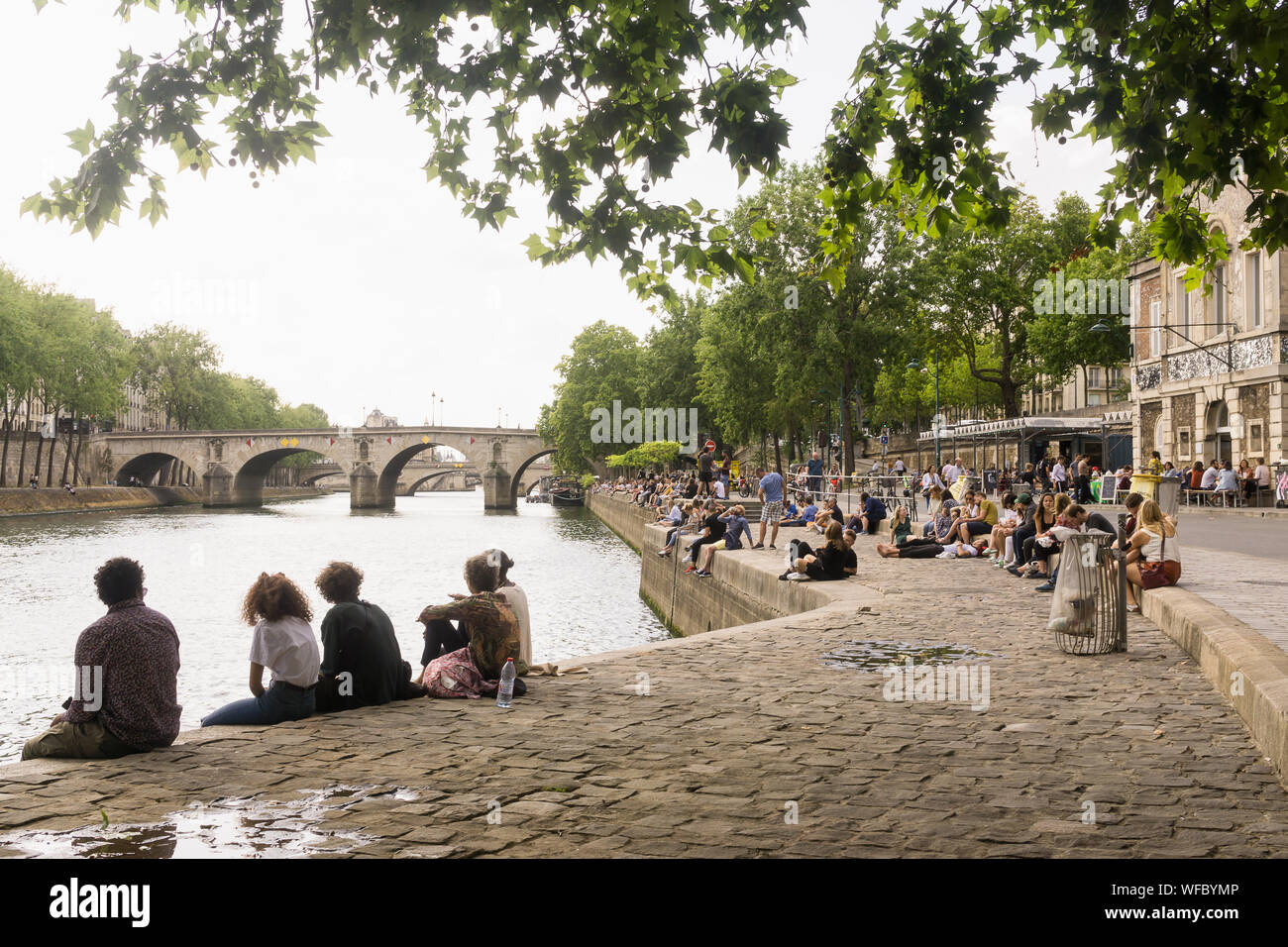 Paris riverbank - people enjoying summer on the Seine riverbank near the cafe bar Les Nautes in the 4th arrondissement of Paris, France, Europe. Stock Photo