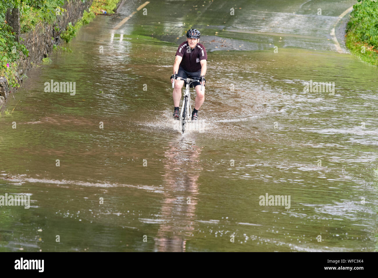 Bardowie, Glasgow, Scotland, UK. 31st Aug, 2019. UK weather - a determined cyclist continues his morning ride regardless of the sections of flooding due to heavy rain overnight and showers this morning in Glasgow Credit: Kay Roxby/Alamy Live News Stock Photo