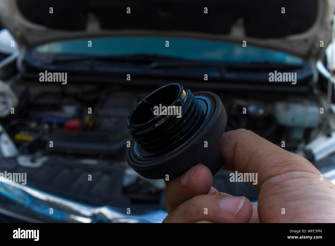 Auto mechanic checking engine oil dipstick in car with oil cap . Auto mechanic in car repair