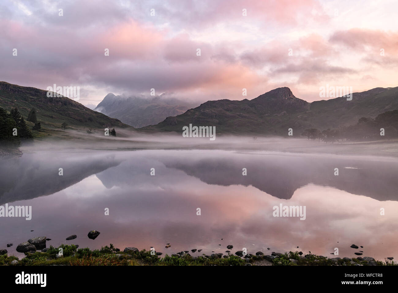 Sunrise at Blea Tarn on a calm misty morning in late summer Stock Photo