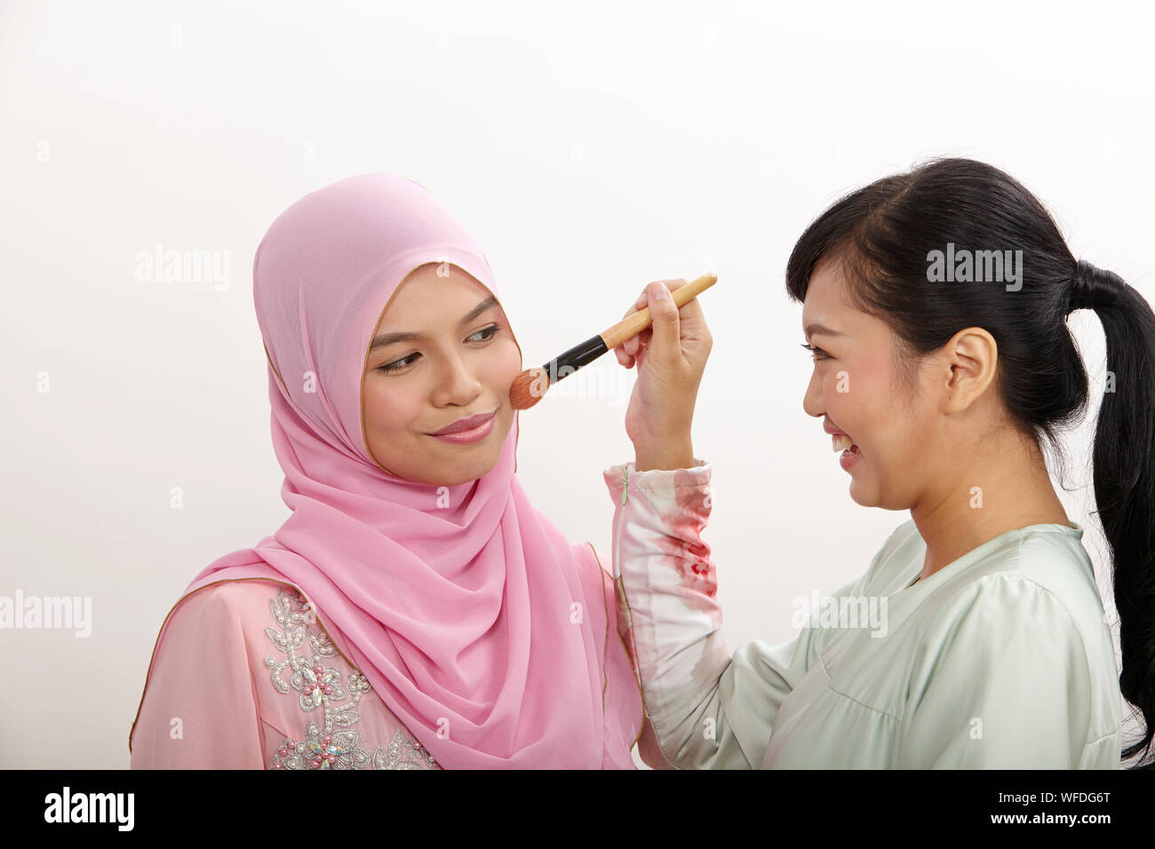 friendship, woman helping her friend putting makeup on the white background Stock Photo