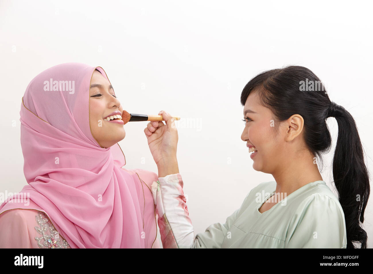 friendship, woman helping her friend putting makeup on the white background Stock Photo