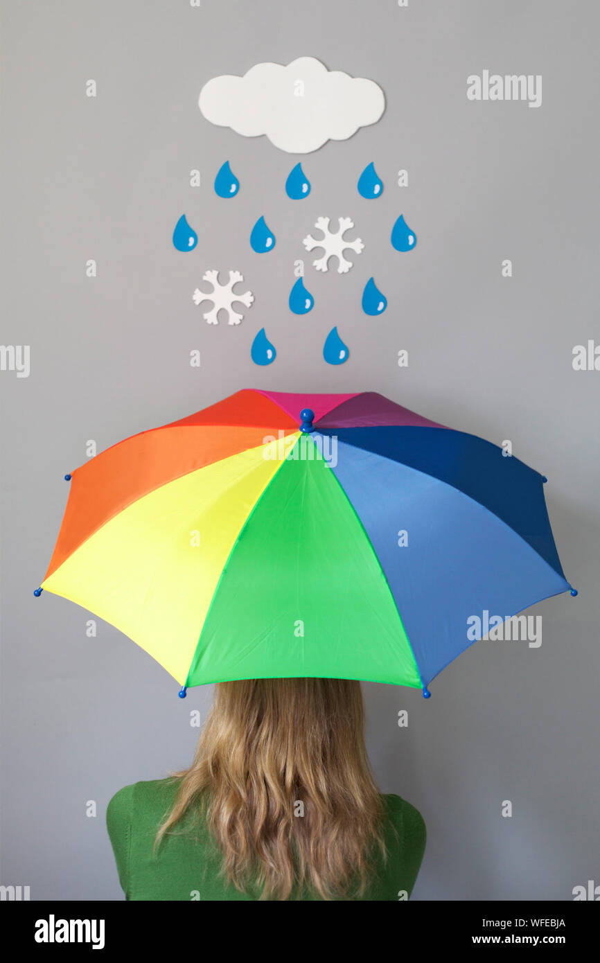 Rear View Of Woman With Colorful Umbrella Standing Against Cloud Art On Gray Wall Stock Photo