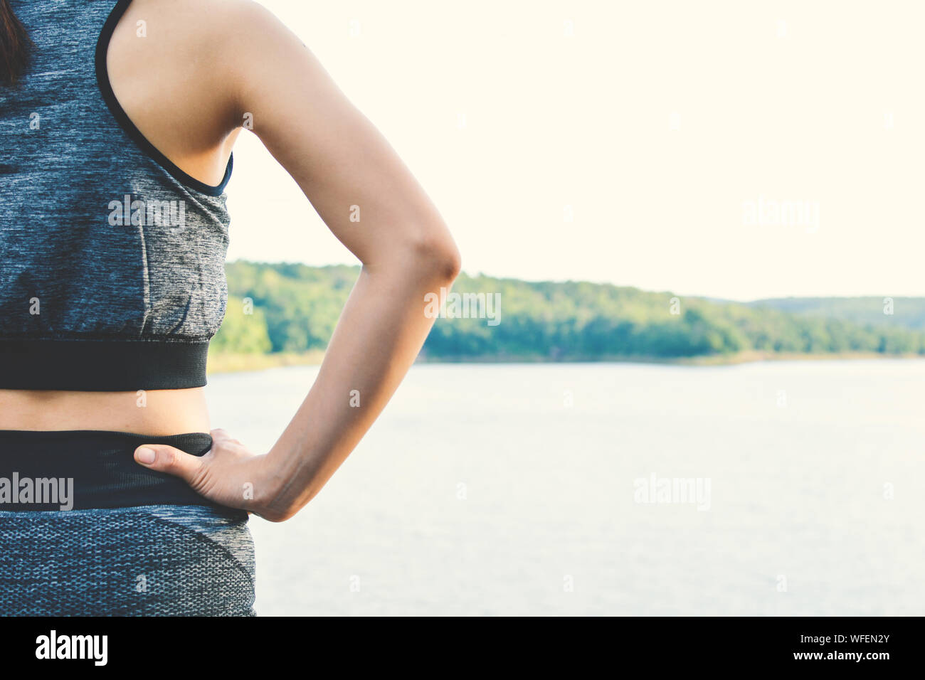 Midsection Of Woman With Hand On Hip Standing By River Stock Photo