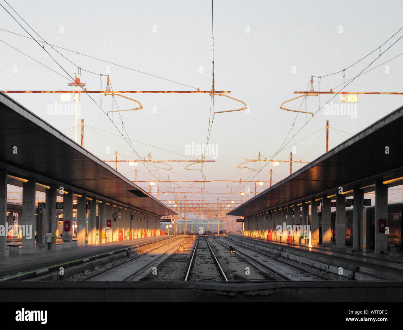 Electricity Cables Over Railroad Tracks Amidst Stations Against Sky