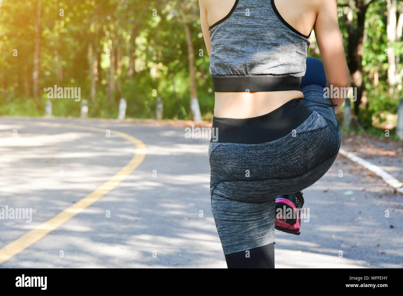 Midsection Of Woman With Sports Clothing Warming Up While Standing Outdoors Stock Photo