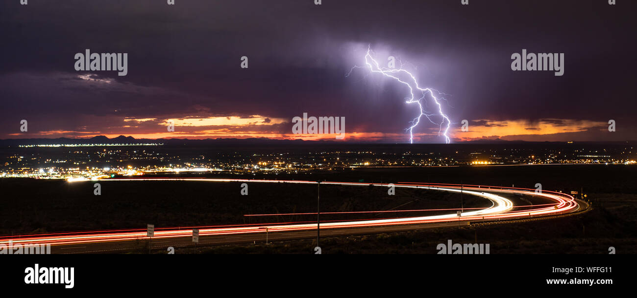Cloud to ground lightning strikes in the Upper Valley of El Paso, Texas, USA, in August 2019, with curving light trails from Transmountain Road. Stock Photo