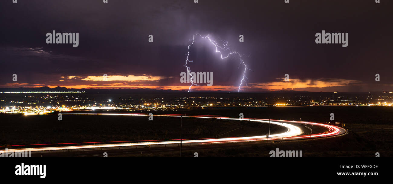 Cloud to ground lightning strikes in the Upper Valley of El Paso, Texas, USA, in August 2019, with curving light trails from Transmountain Road. Stock Photo