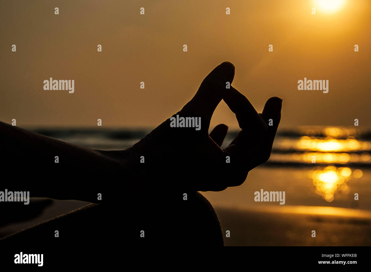 Silhouette Hand In Meditating Posture Stock Photo