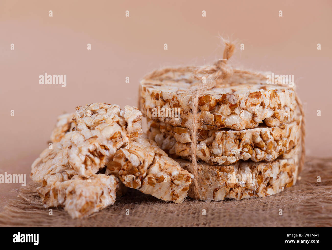 Round cereal crispbread tied with rope, crumbs on surface. Rustic style. Stock Photo