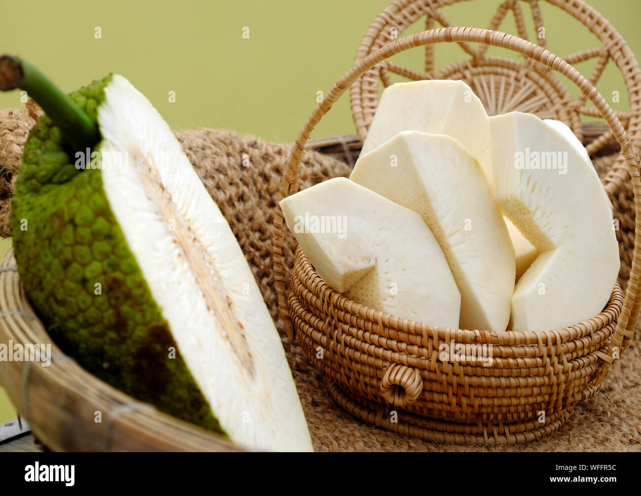 Close up breadfruit cut in half and slice in handmade basket on yellow background, Vietnamese vegetarian dish Stock Photo