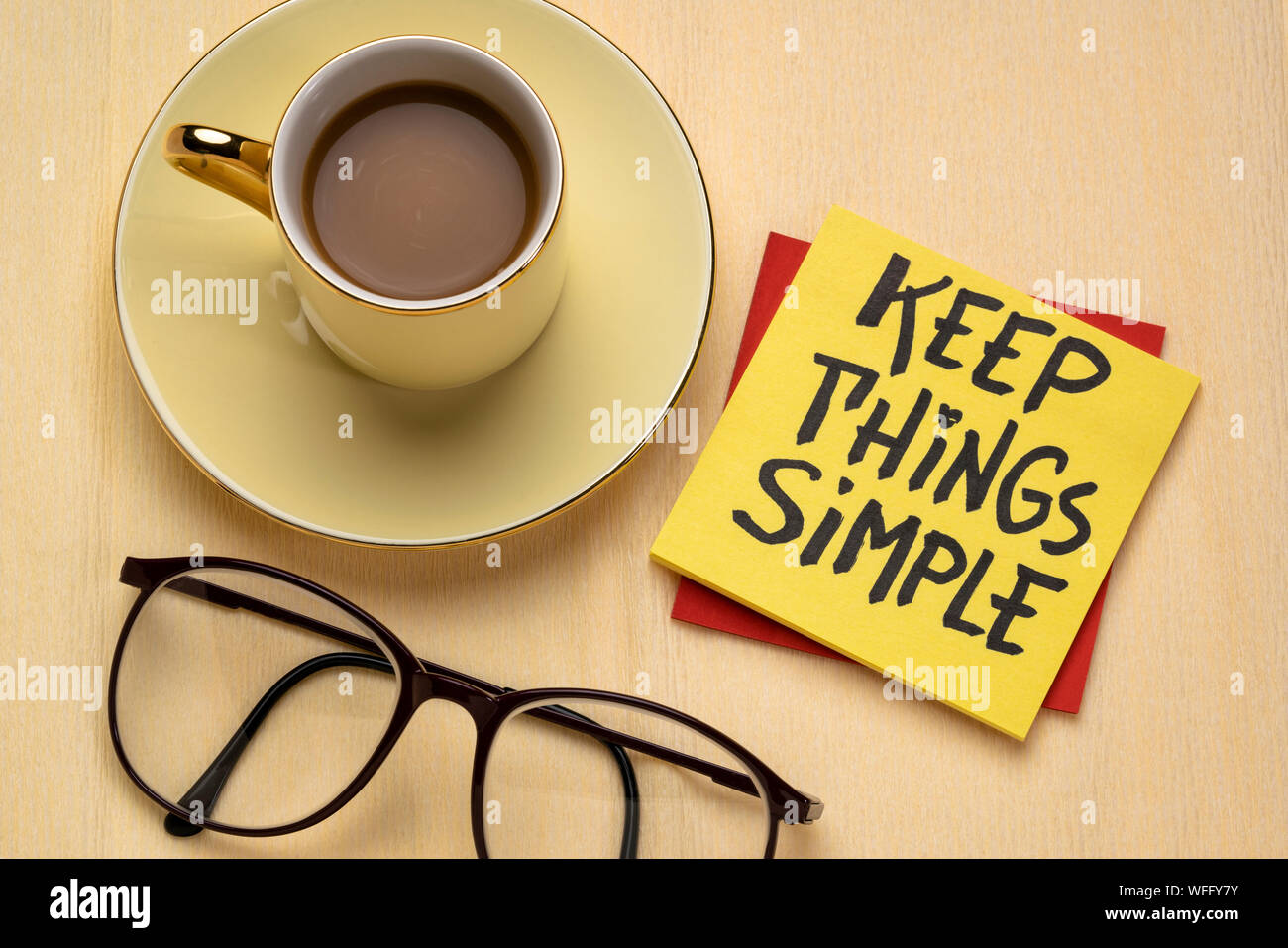 Keep things simple - handwriting on a reminder note with a cup of coffee, efficiency or minimalism concept Stock Photo