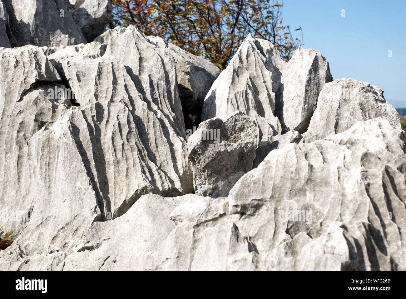 Rocks On Cliff Against Mountain Stock Photo