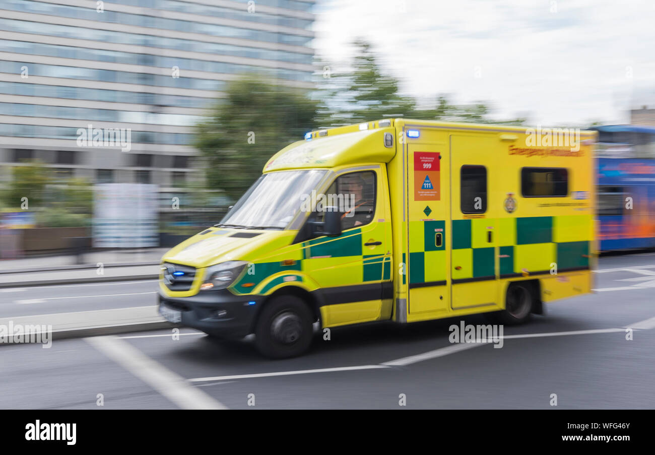 London Ambulance Service NHS ambulance on a call with blue lights, showing movement blur from moving fast, in Central London, England, UK. Stock Photo