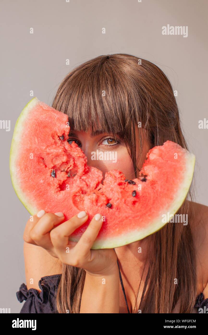 Woman hiding behind a slice of watermelon Stock Photo