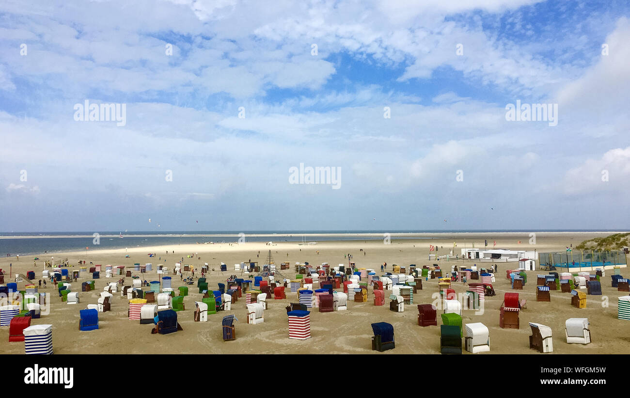 Various Strandkorb At Beach Against Cloudy Sky Stock Photo