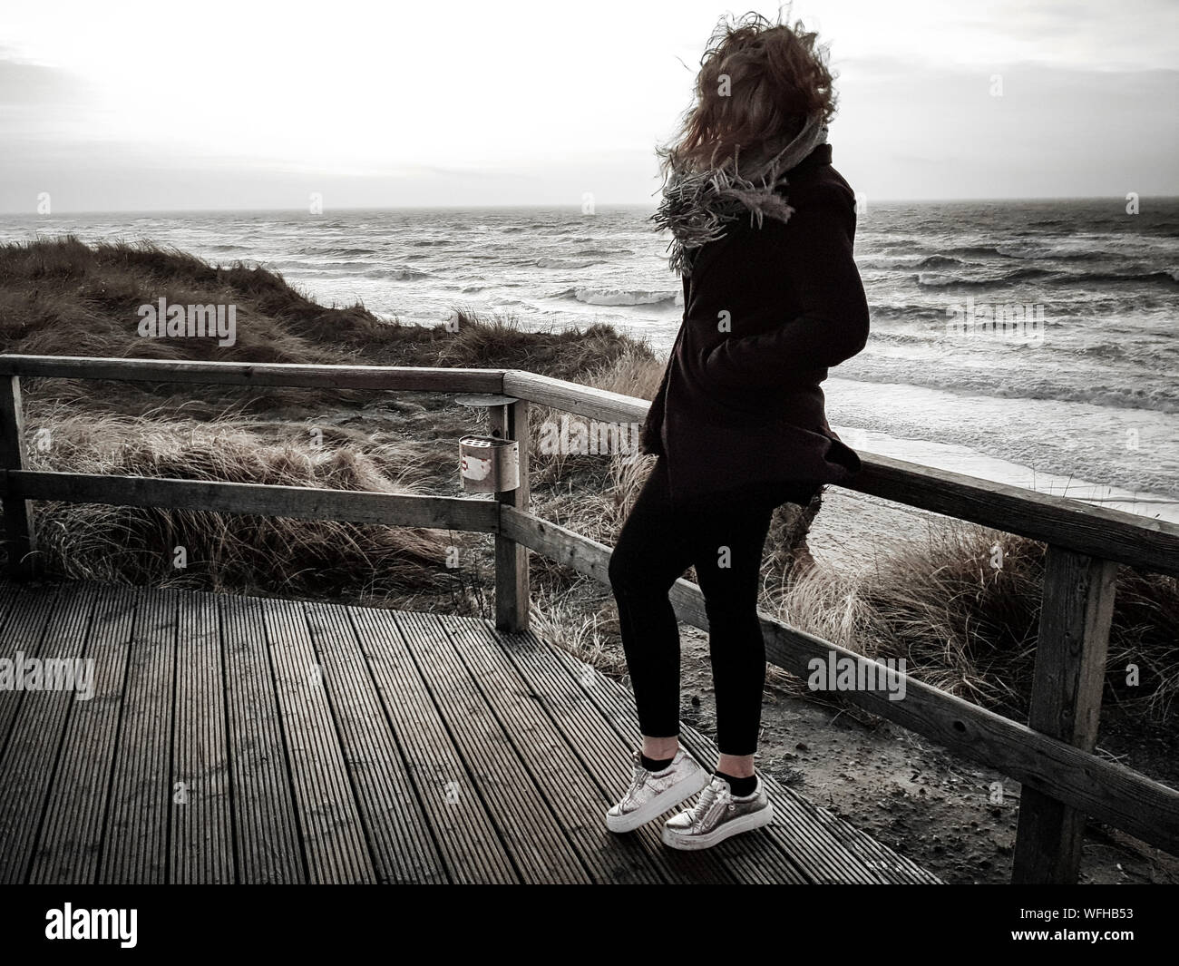 Full Length Of Woman With Tousled Hair Standing On Boardwalk At