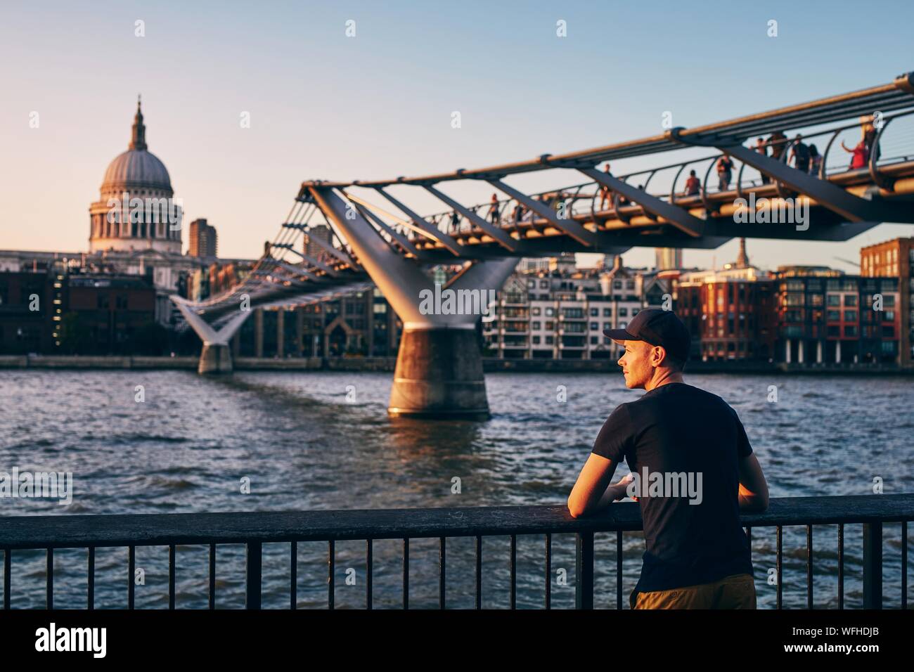 Young man relaxing on riverside against urban skyline. Contemplation at sunset. London, United Kingdom. Stock Photo