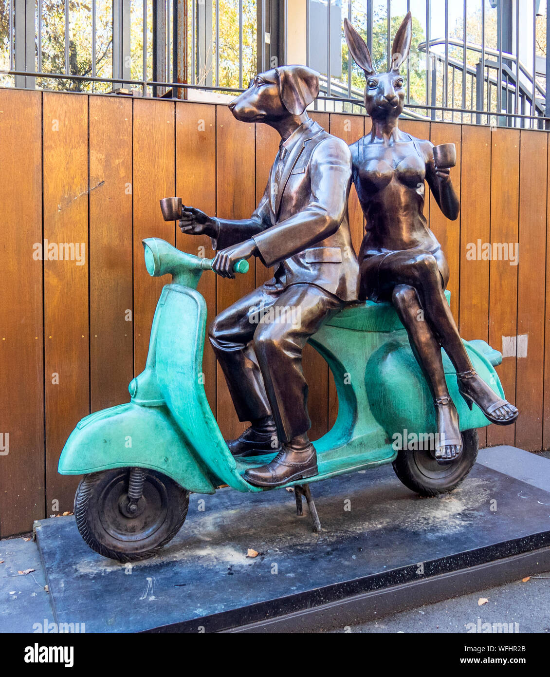 Bronze sculpture of Dogman and Rabbitwoman on a Vespa by sculptors Gillie and Marc Schattner located in Surrey Hills Sydney NSW Australia. Stock Photo