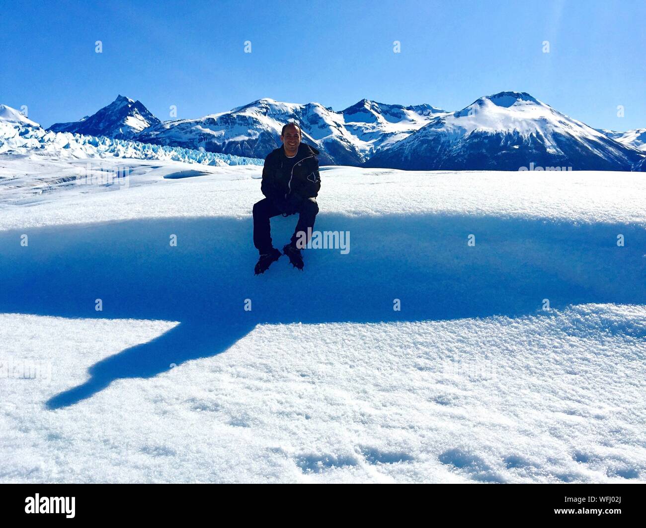 Man Sitting On Snowy Field At Glaciar Perito Moreno Stock Photo
