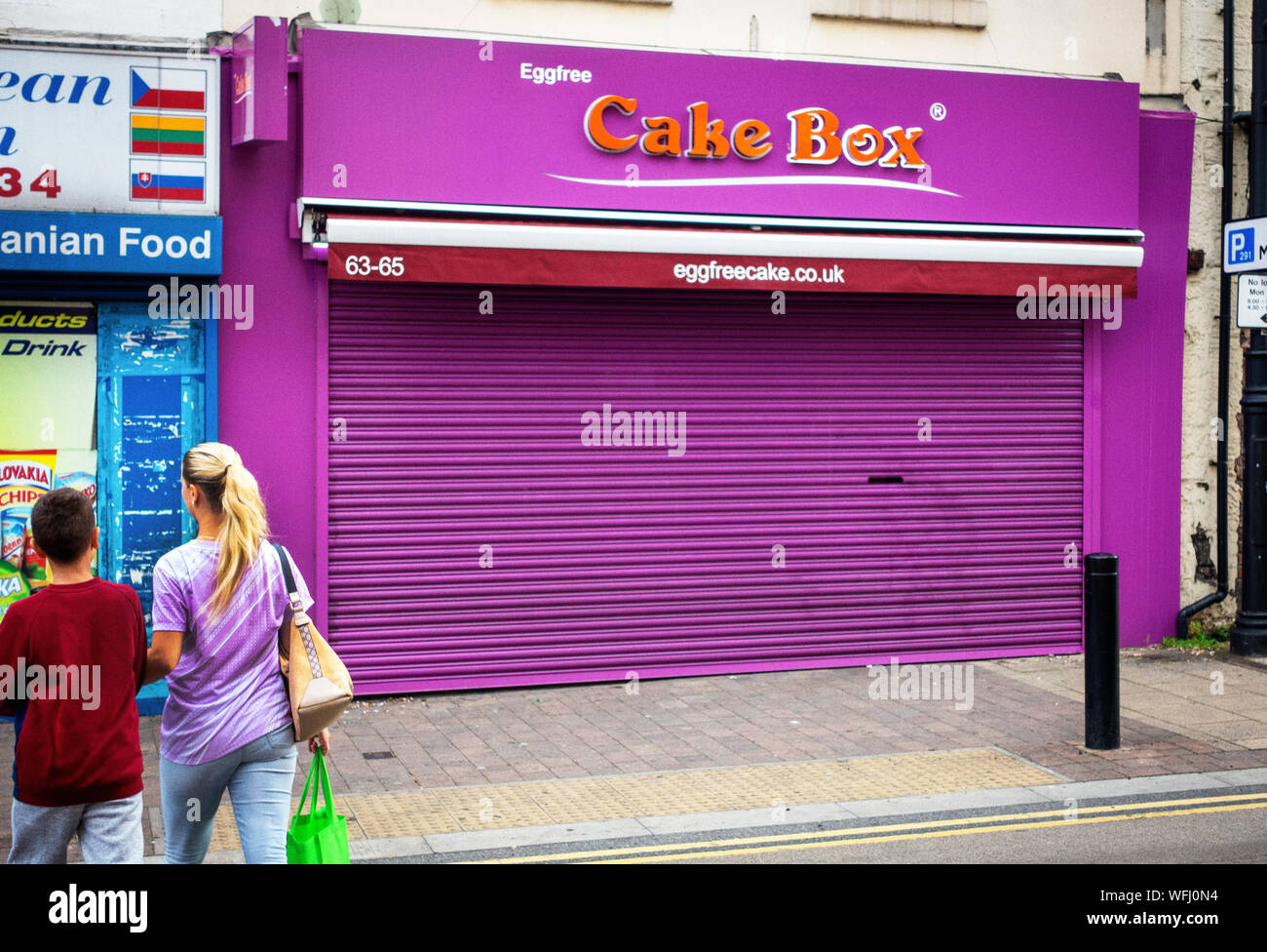 two people walking near closed shuttered shop in Rotherham Stock Photo