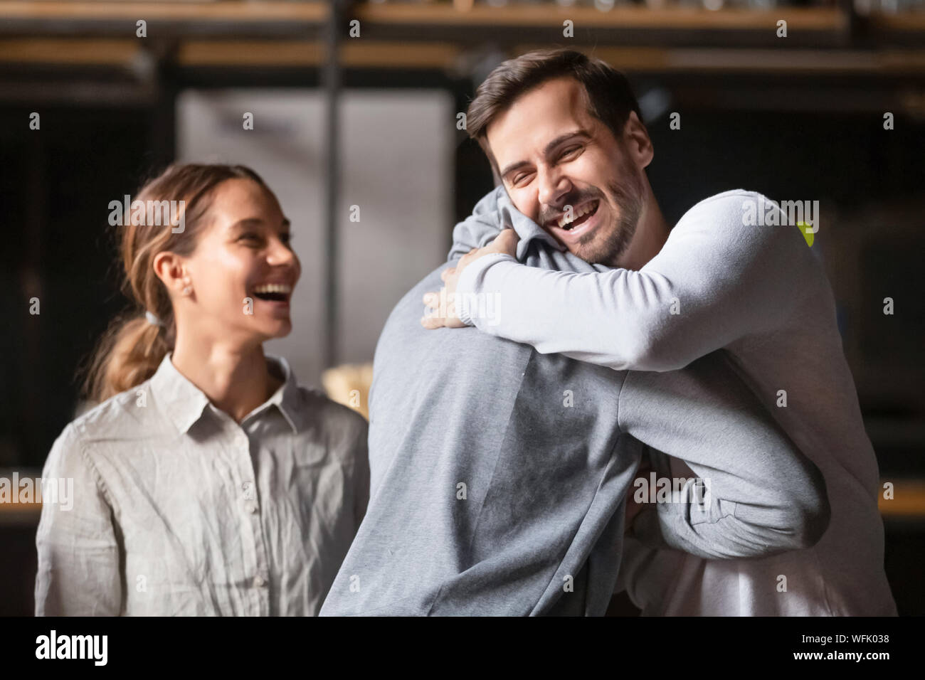 Happy diverse male buddies embracing laughing greeting in cafe Stock Photo