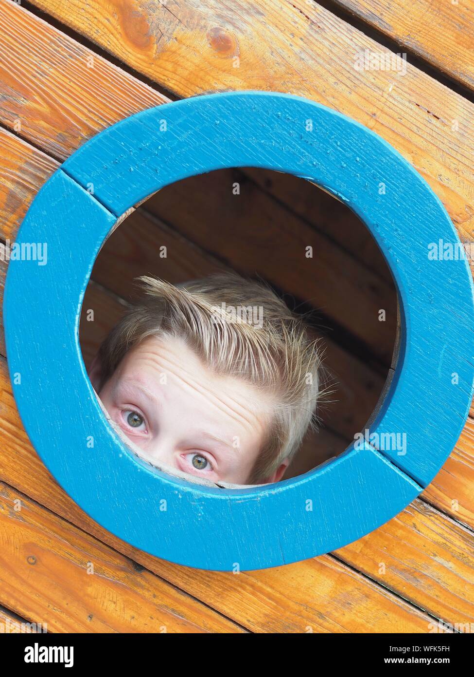 Close-up Of Boy Peeking Out Of Window Stock Photo