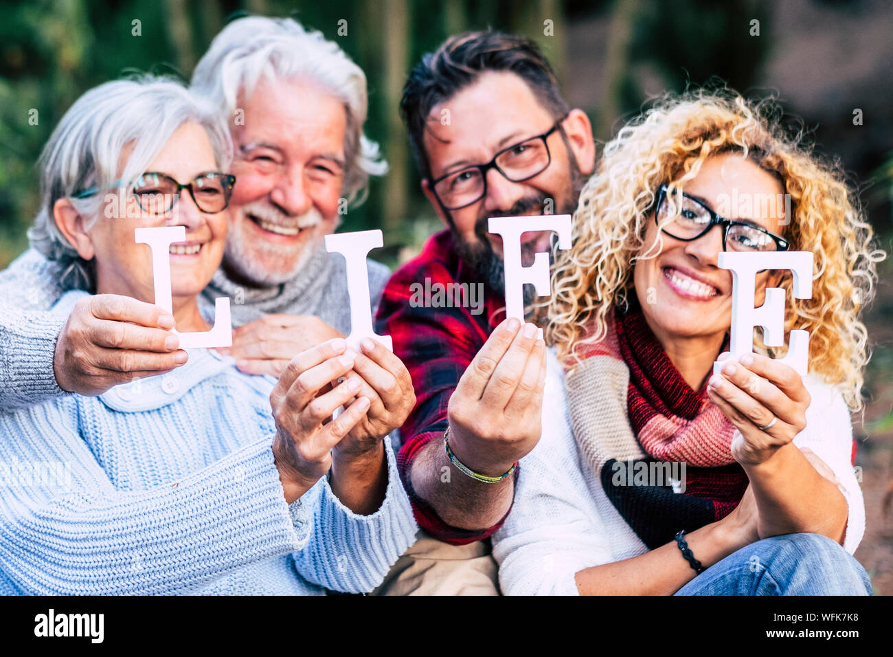 Group of mixed ages generations people smiling and showing blocks letters with  life word -  happy lifestye enjoying the outdoor leisure activity toge Stock Photo